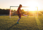 girl kicking soccer ball at dusk