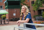 Female nurse in front of a building smiling and staring far off.