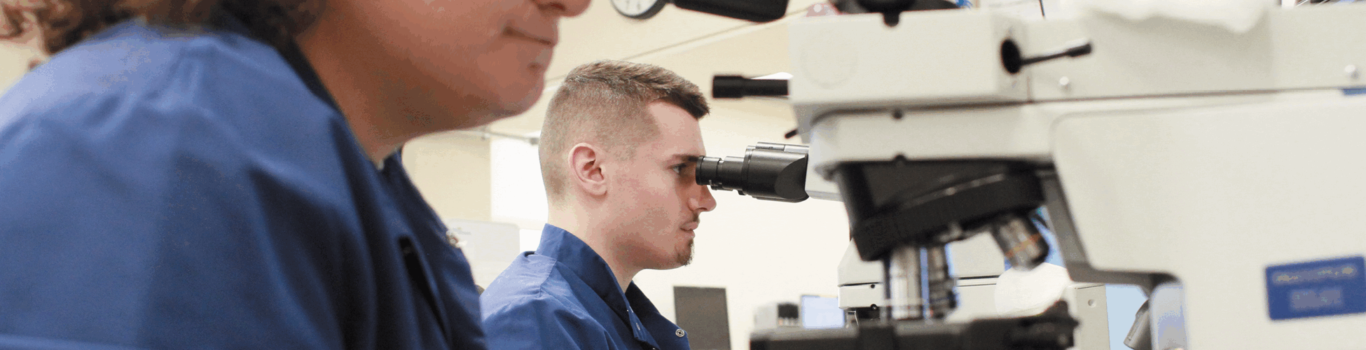 Two lab technicians looking at samples through a machine.