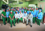 Group of doctors and nurses in the operating room posing for a group photo.
