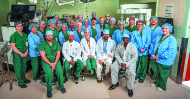Group of doctors and nurses in the operating room posing for a group photo.