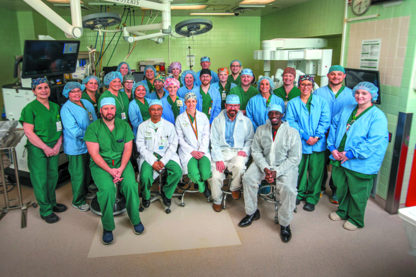 Group of doctors and nurses in the operating room posing for a group photo.